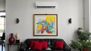 Wall-mounted mini-split air conditioner above a black leather sofa in a modern living room.