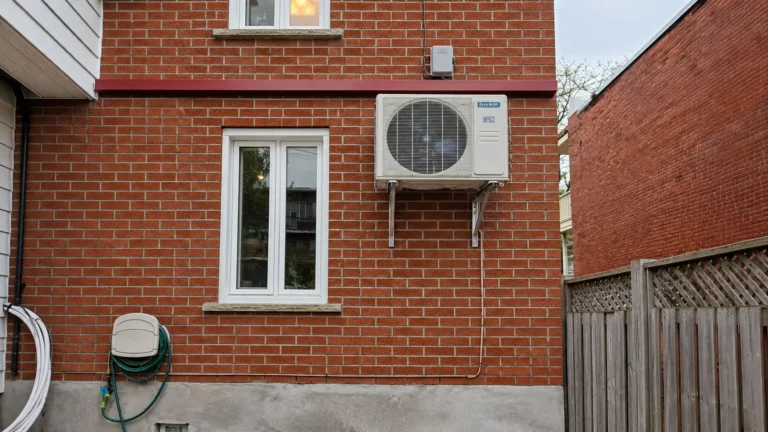 Franklin outdoor heat pump mounted on a red brick house wall beside white-framed windows.
