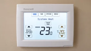 Honeywell wall thermostat displaying 23°C indoor temperature, 20°C set temperature, and System Wait status.