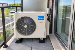 Midea outdoor mini-split unit installed on a condo balcony beside a sliding glass door.