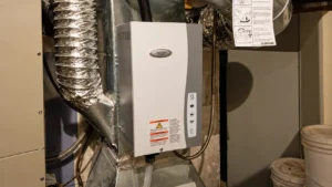 Aprilaire whole-home humidifier mounted on HVAC ductwork in a basement utility room.